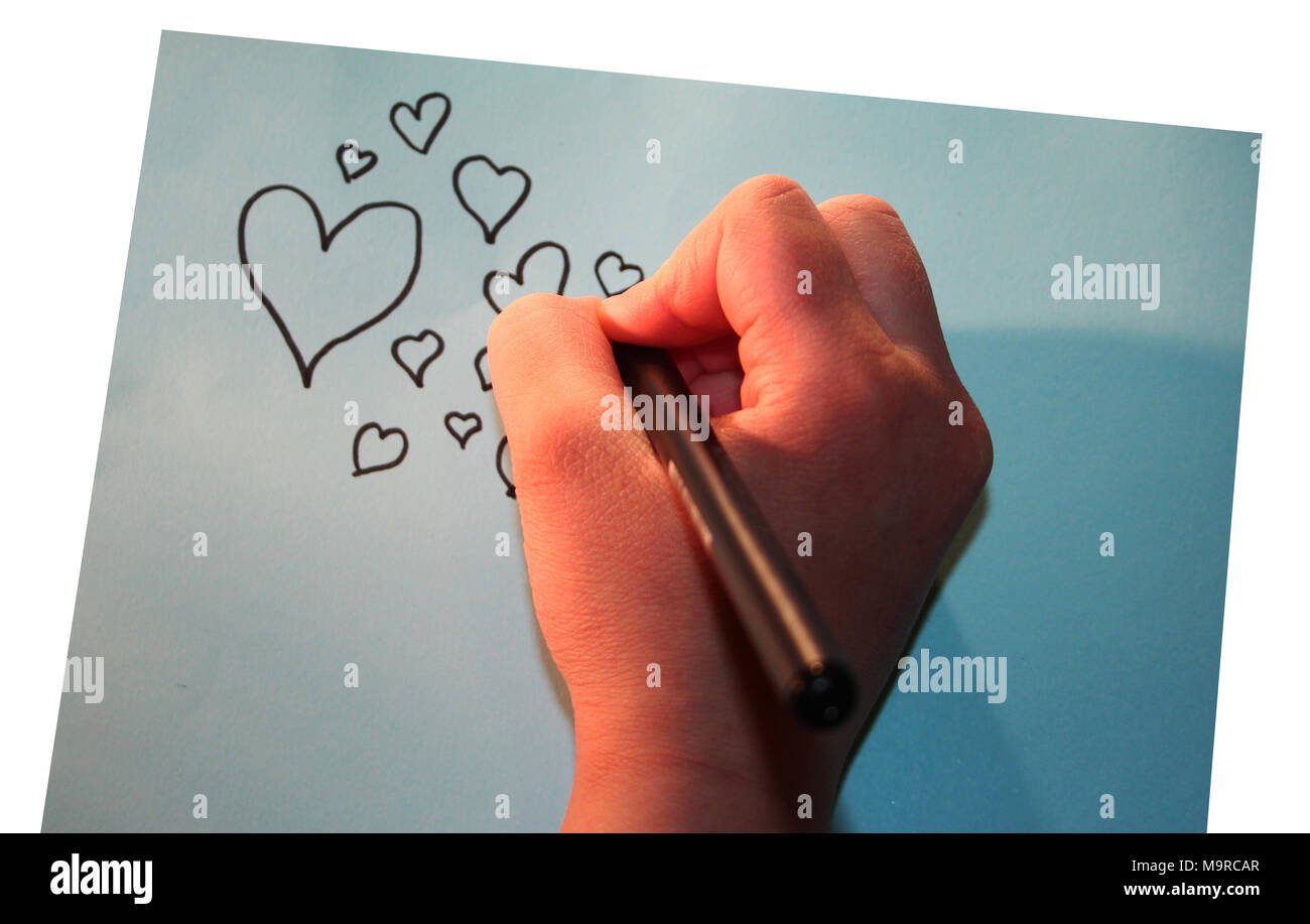 Girl drawing hearts into paper Stock Photo
