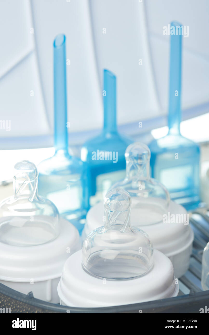 Milk bottles sterilizing theme. Cleaning nipple from bacteria Stock
