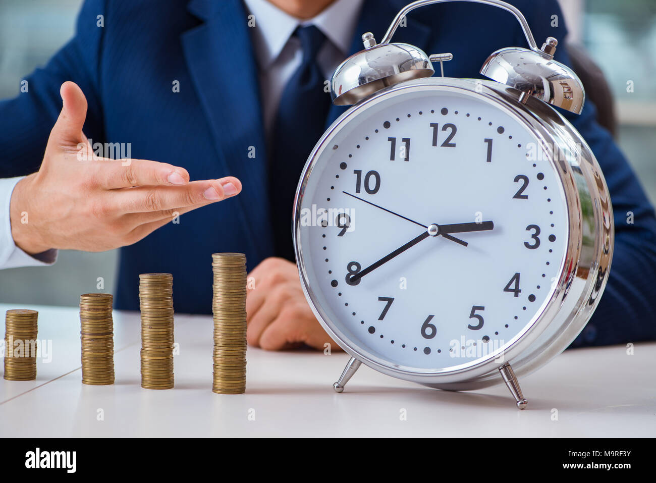 Businessman with stacks of coins in the office Stock Photo - Alamy