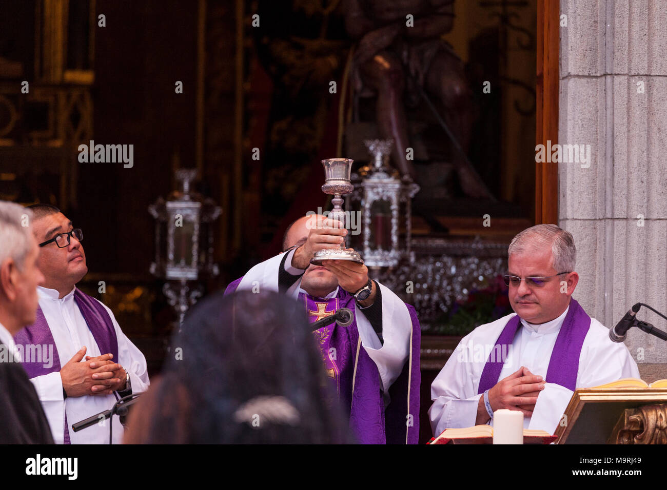 Priest celebrating mass, holding up a chalice of wine, outside the ermita de La Viña in Adeje old town, Tenerife, Canary Islands, Spain Stock Photo