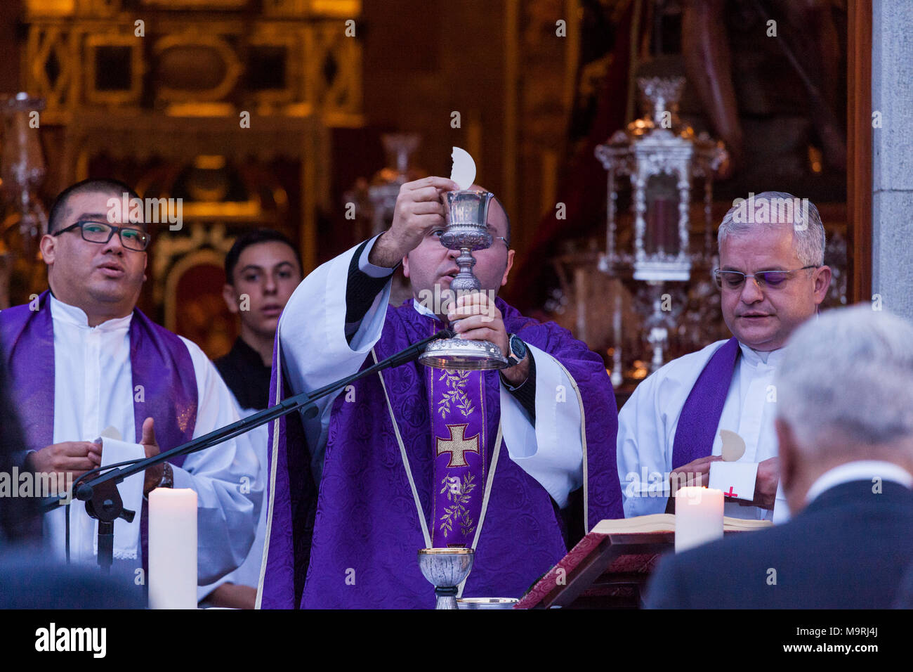 Priest celebrating mass, holding the host and chalice of wine, communion, outside the ermita de La Viña in Adeje old town, Tenerife, Canary Islands, S Stock Photo