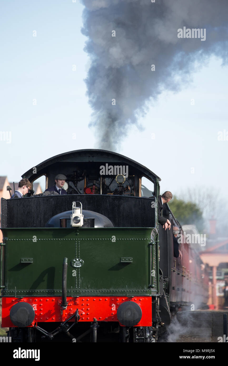 Portrait shot: rear view (tender first) of preserved manor class steam locomotive awaiting departure; crew gets ready for first Sunday morning ride. Stock Photo