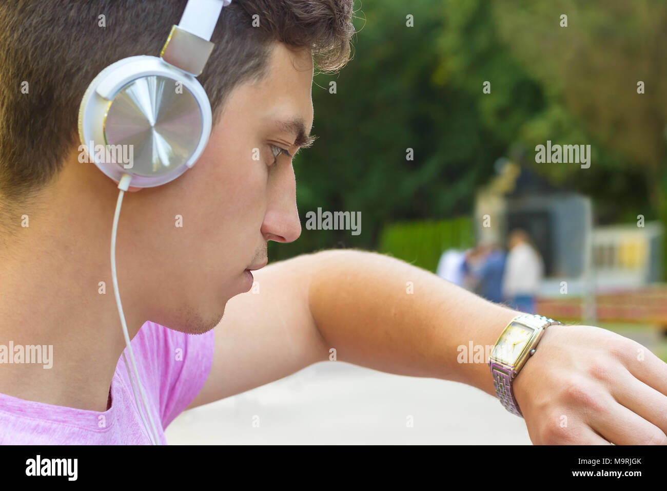 young men looking on a wrist watch and wearing a headphones Stock Photo