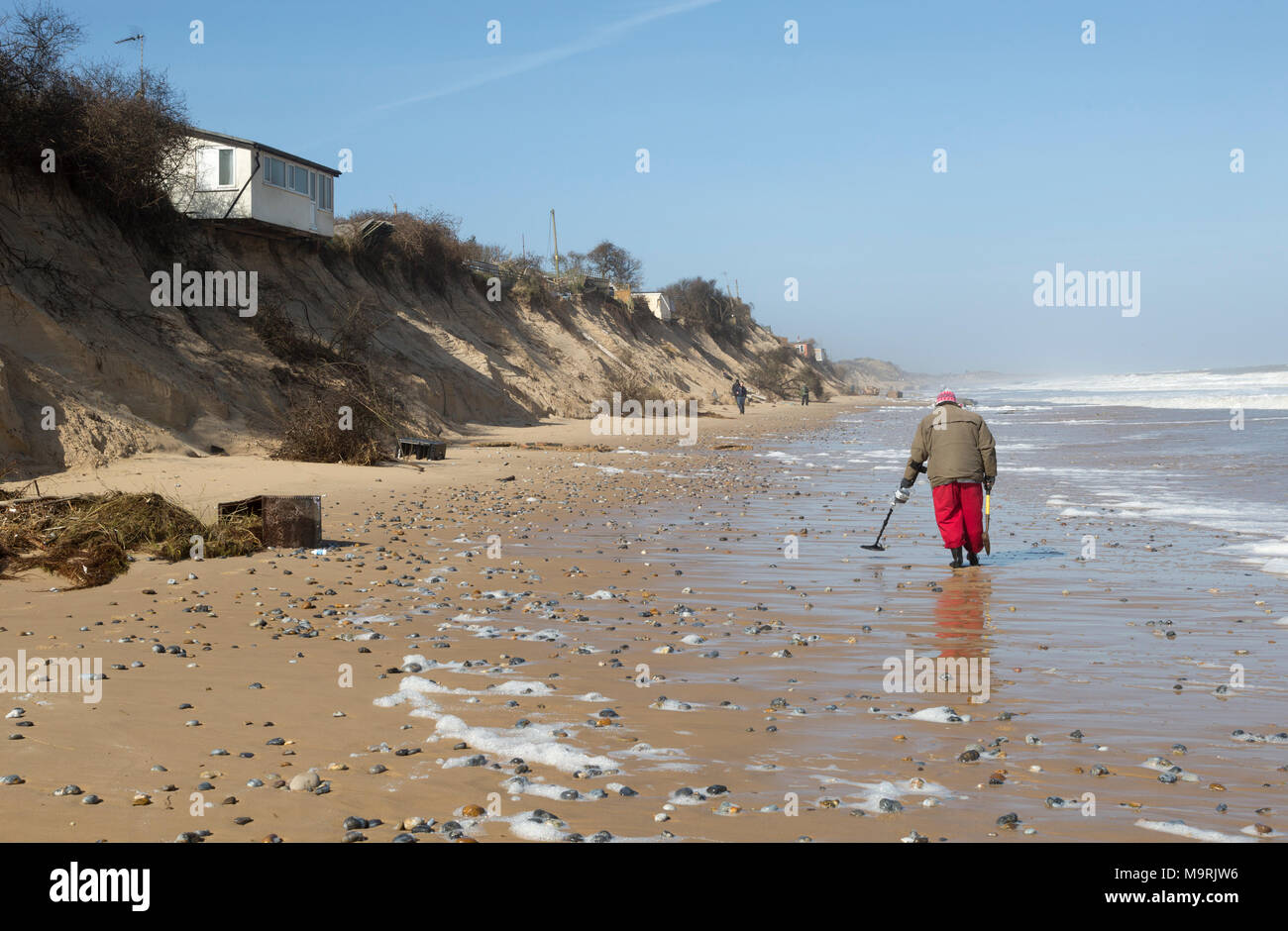 Male  detectorist using metal detector walking along sandy beach Hemsby, Norfolk, England, UK Stock Photo