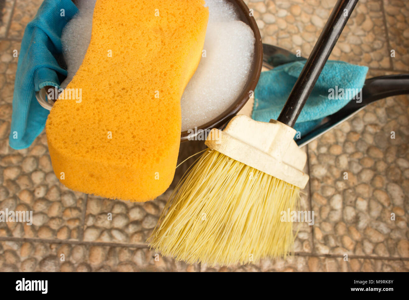 Bucket with water and soap. Sponge is in foreground and rights is broom