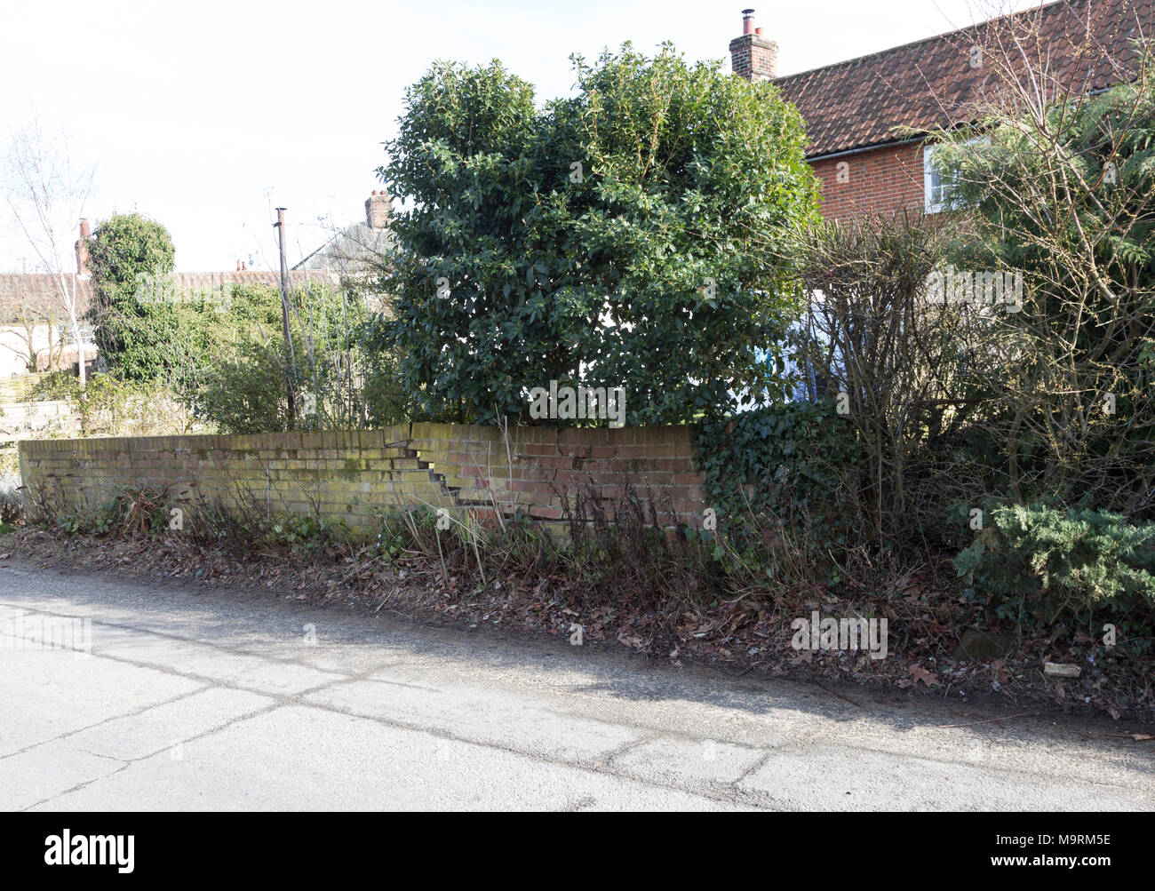 Impact damage to red brick garden wall caused by vehicle reversing, Suffolk, England, UK Stock Photo