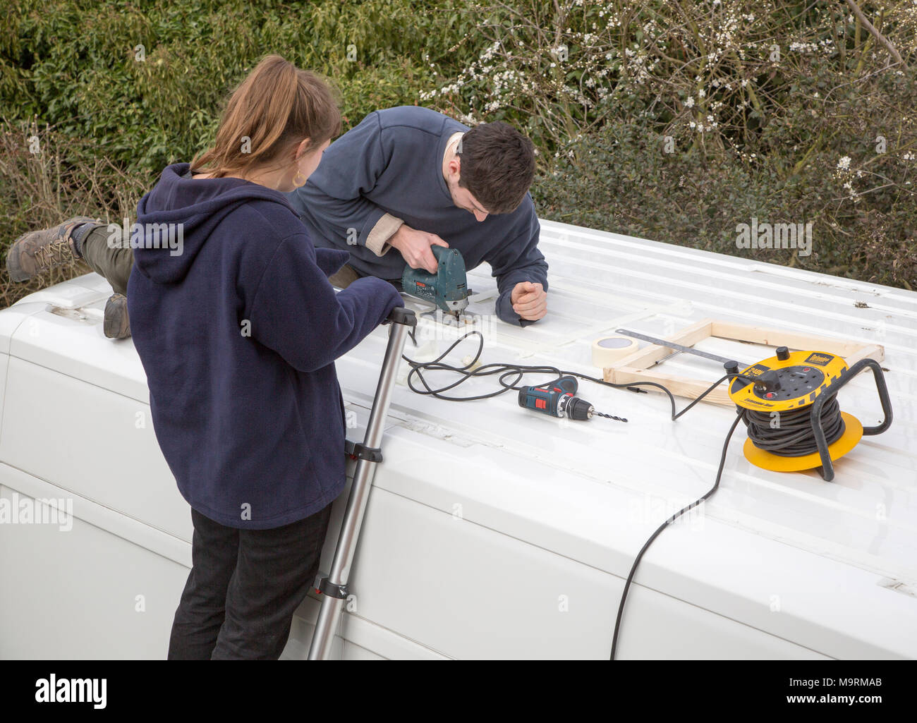 Cutting through roof of white metal camper van conversion to install roof light ventilation