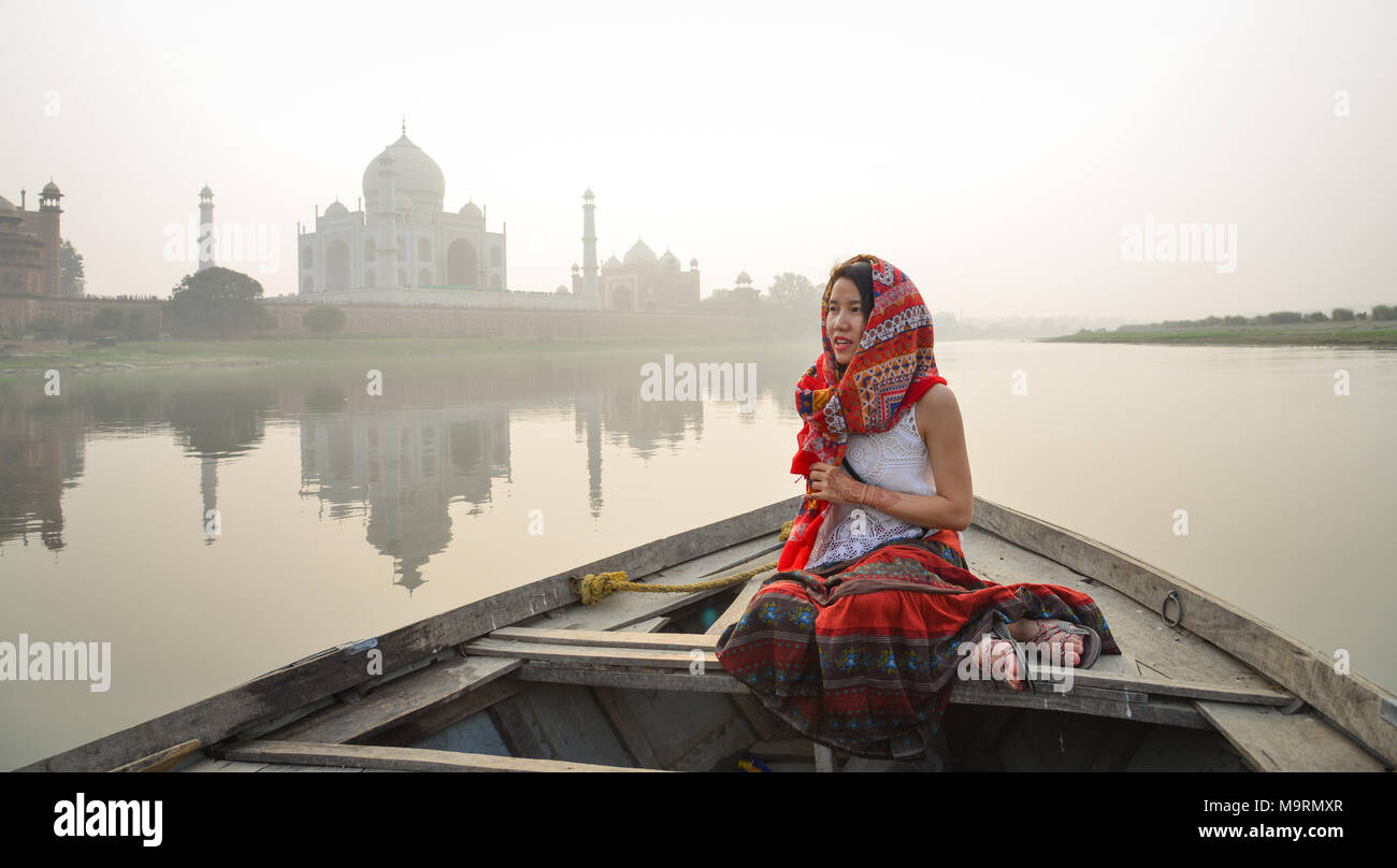 A woman watching sunset over Taj Mahal from a wooden boat. Stock Photo