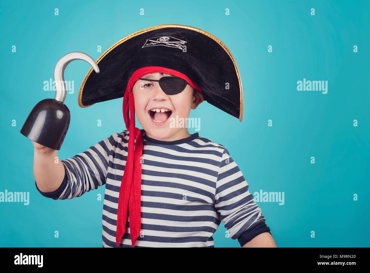 smiling boy dressed as a pirate on blue background Stock Photo