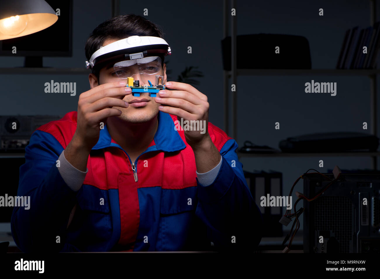 Computer specialist repairing PC late at night Stock Photo - Alamy