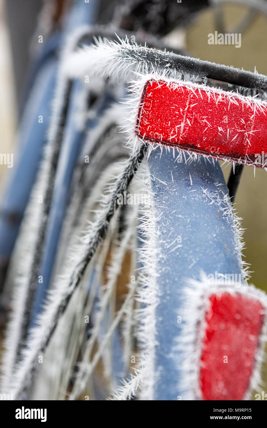 Frozen red reflector by fog on a blue bicycle. Stock Photo