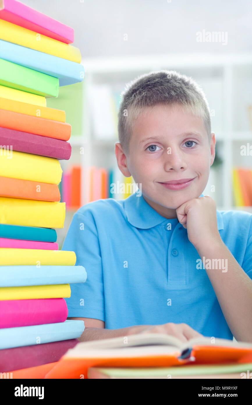 young boy learns at home, a lot of books on the table Stock Photo