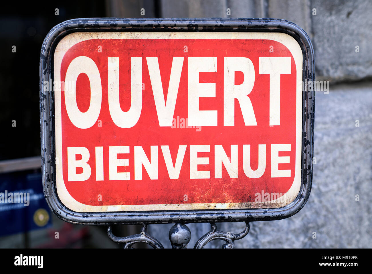 closeup of an old signboard with the text ouvert bienvenue, open welcome written in french, on the street in front of a store or a restaurant Stock Photo
