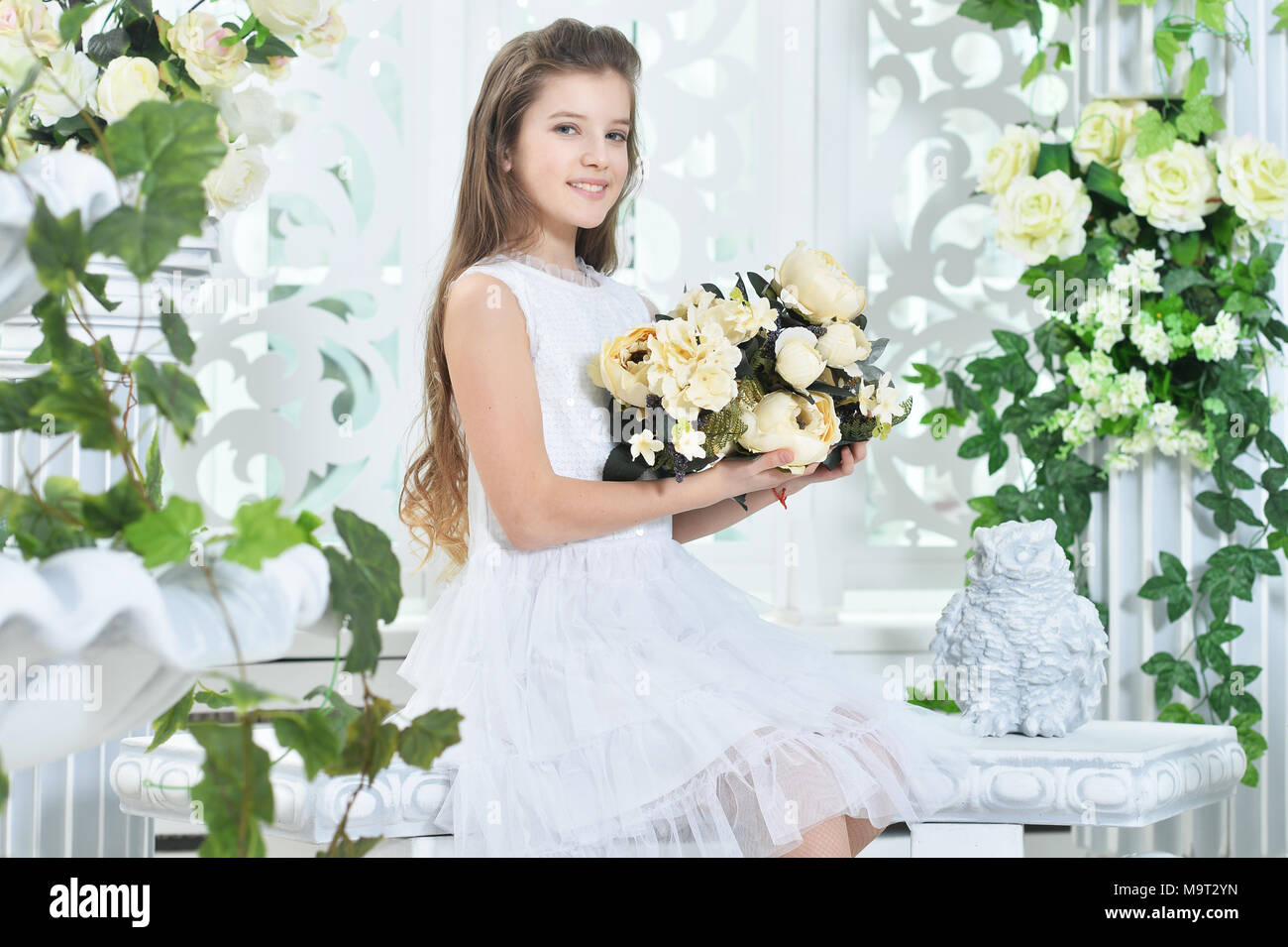 Happy little girl in white dress posing with flowers Stock Photo - Alamy