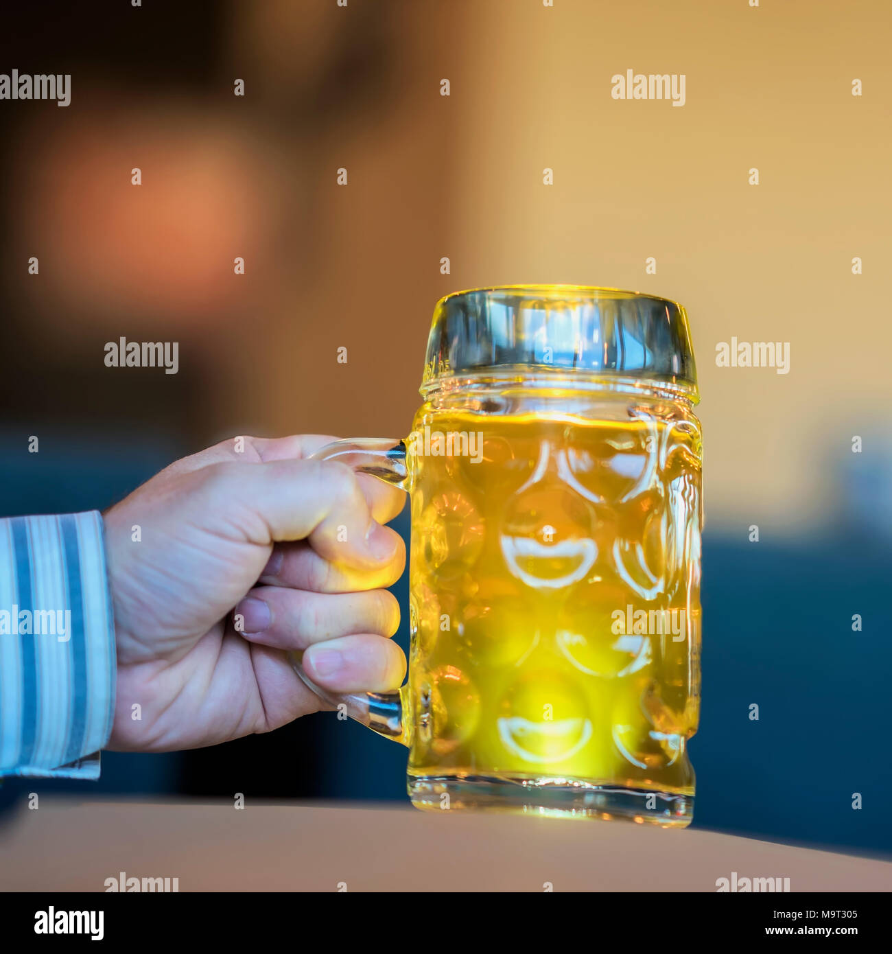 Men Hand with glass mug of golden Freshly filled beer. Real scene in bar, pub. Beer culture, Craft brewery, uniqueness beer grades, meeting of low alcohol beverage lovers Stock Photo