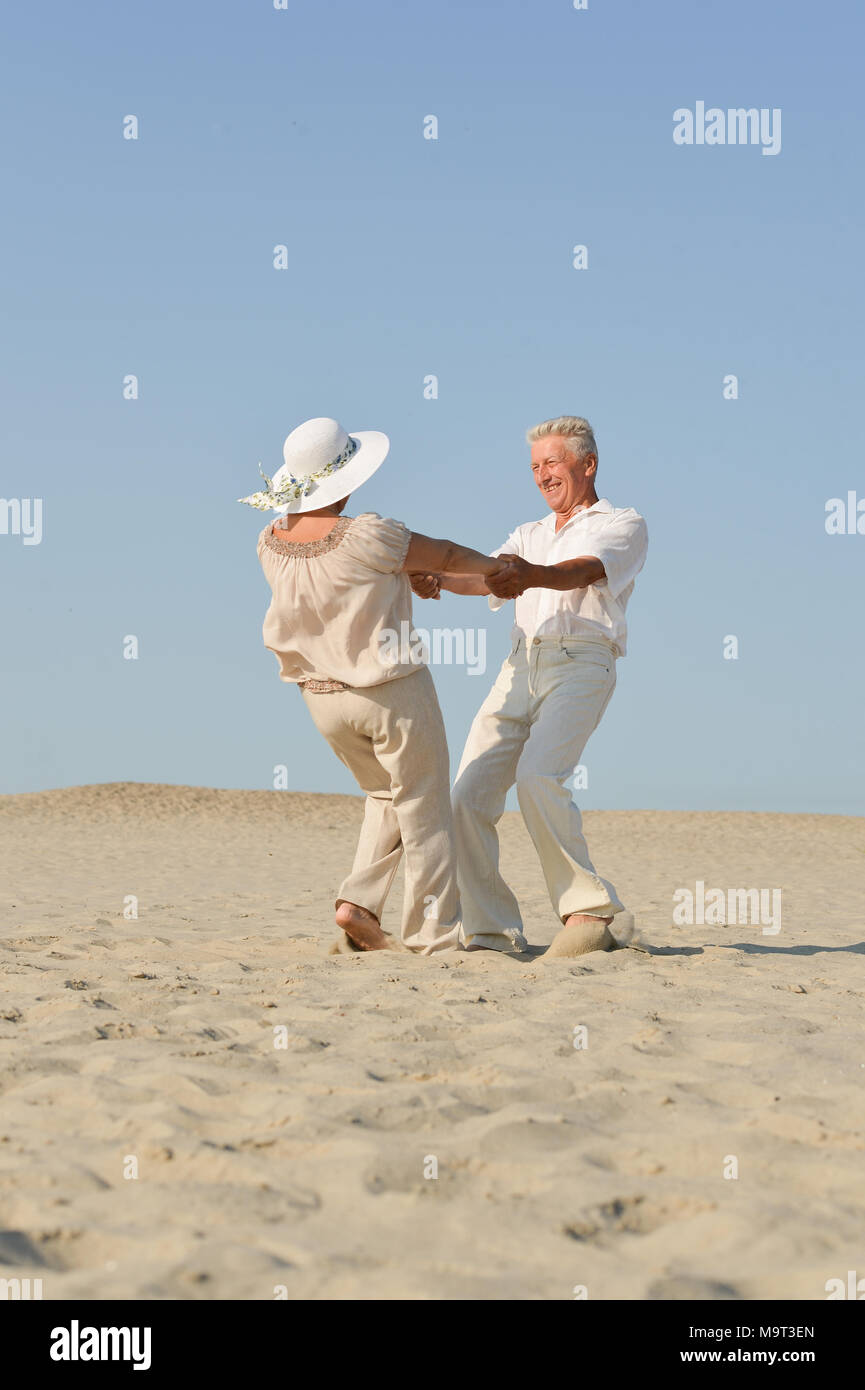 older couple in love walking barefoot in the sand Stock Photo