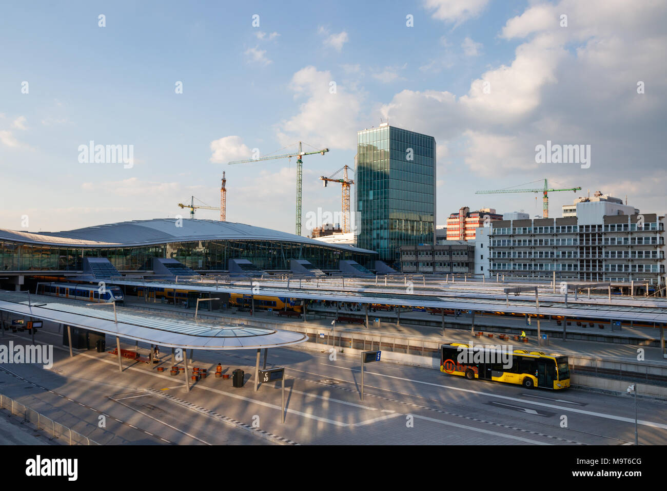 The NS hea quarters, platforms of Utrecht Centraal Railway Station and the bus station with a leaving bus on a sunny day.  Utrecht, The Netherlands. Stock Photo