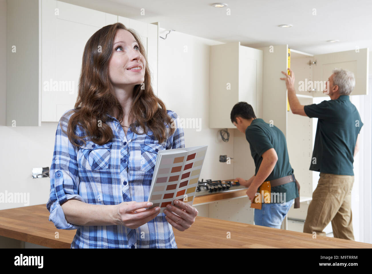 Woman Looking At Paint Chart In New Kitchen Stock Photo