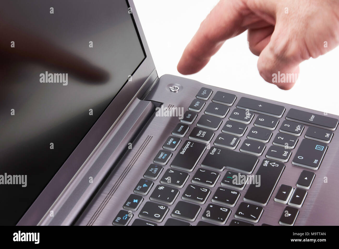 Silver laptop and moving man's hand catching start button, isolated on white background Stock Photo