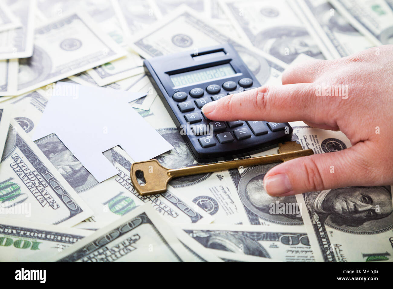 Cardboard house,calculator and key on the money. Buying a property