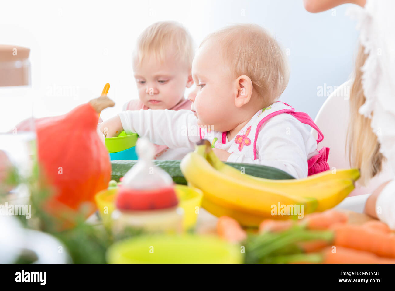Cute baby girl eating healthy solid food in a modern daycare cen Stock Photo
