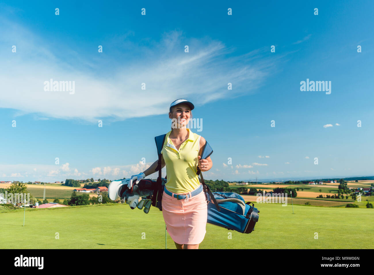 Full length rear view of an active woman carrying a blue stand bag Stock Photo