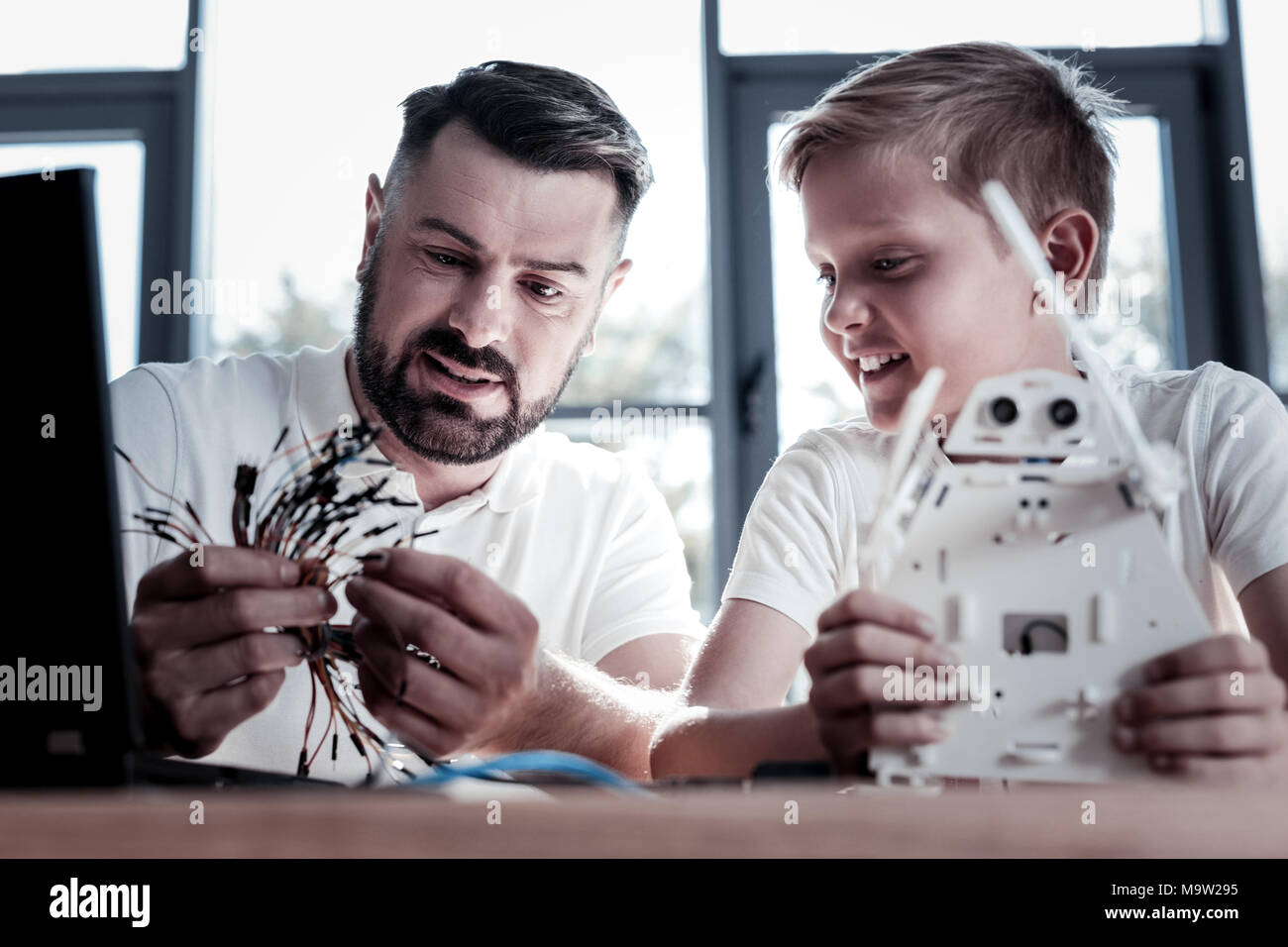 Excited father and son constructing robotic machine at home Stock Photo ...