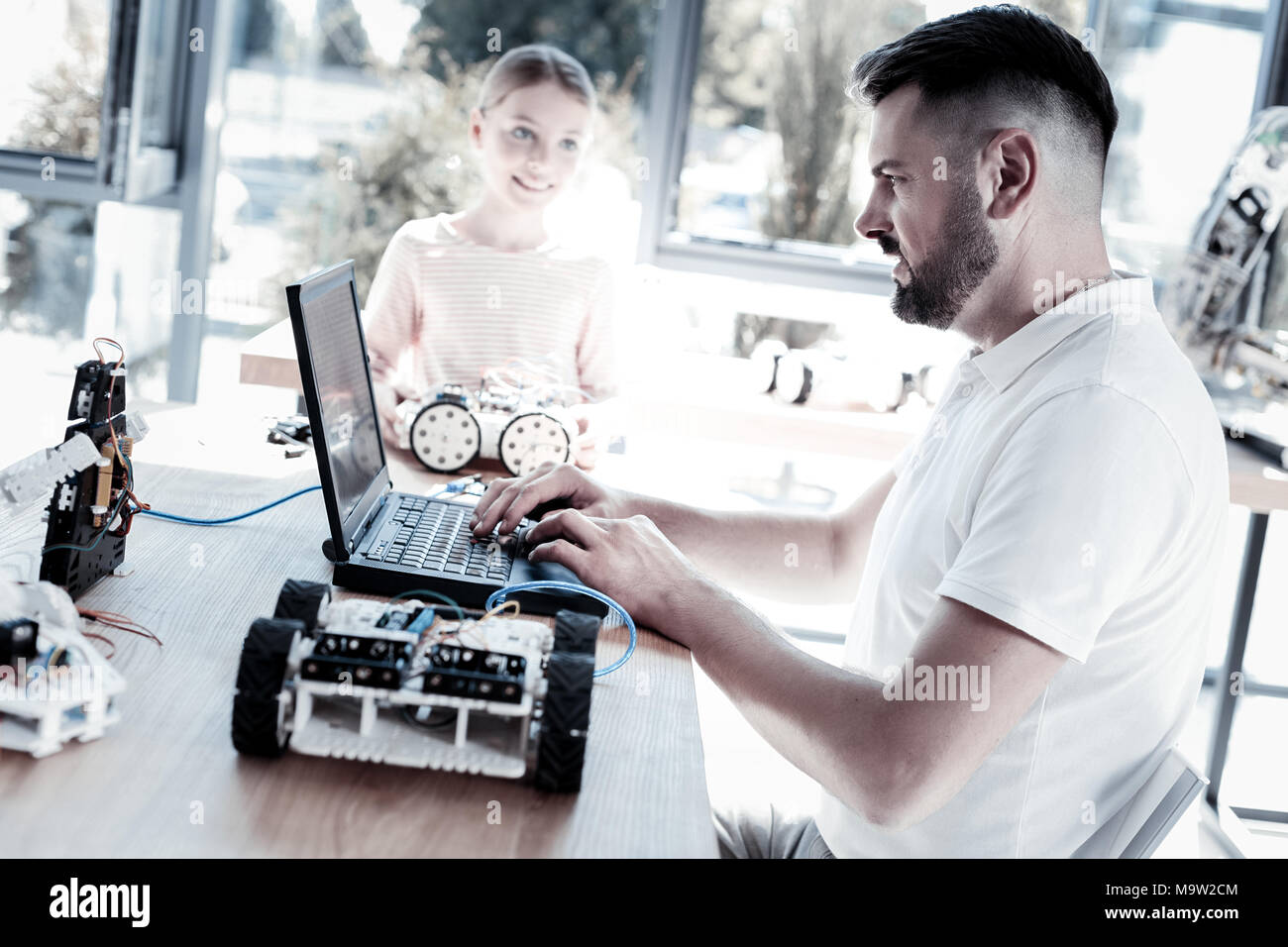 Serious teacher programming robot of his student Stock Photo