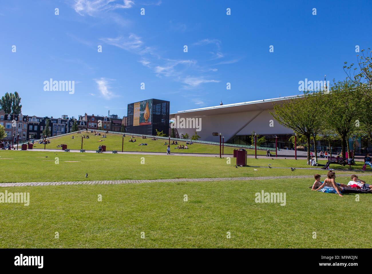 People relaxing on the gras near the Stedelijk Museum in Amsterdam. Stock Photo