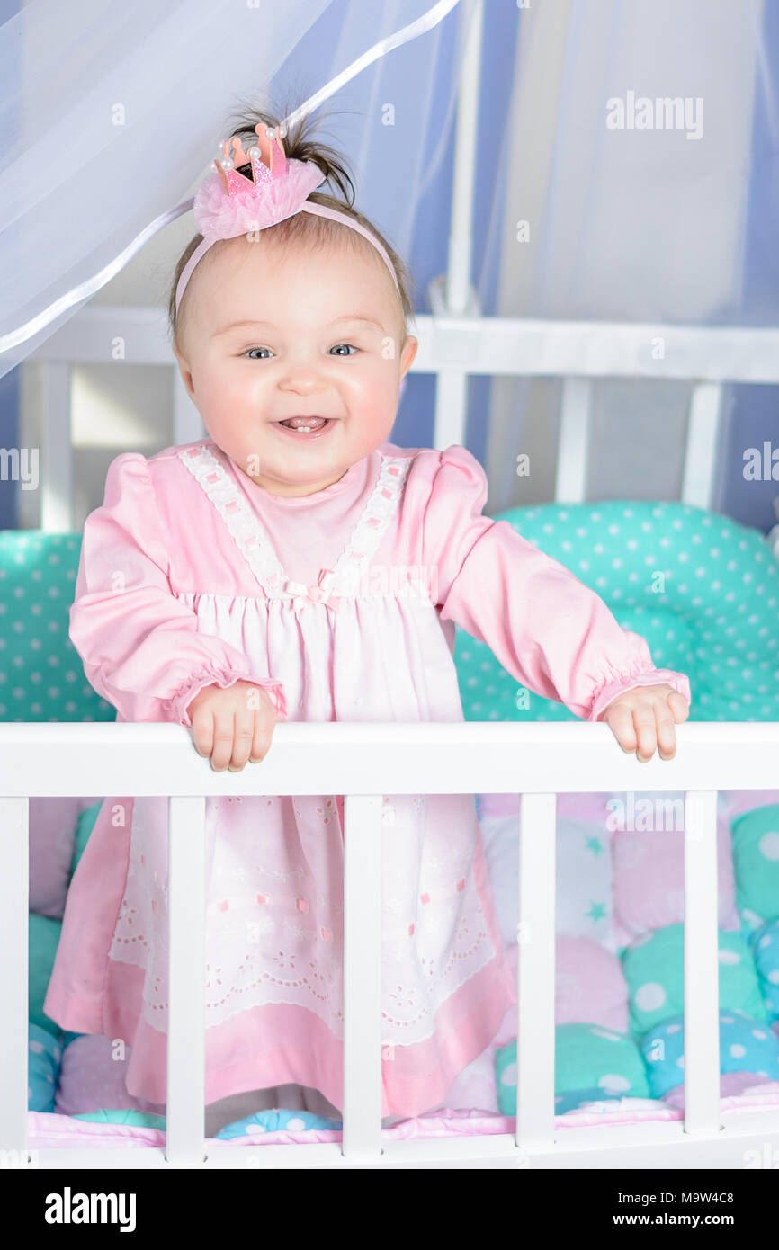 Little beautiful girl in a pink dress laughs in a baby bed 2018 Stock ...