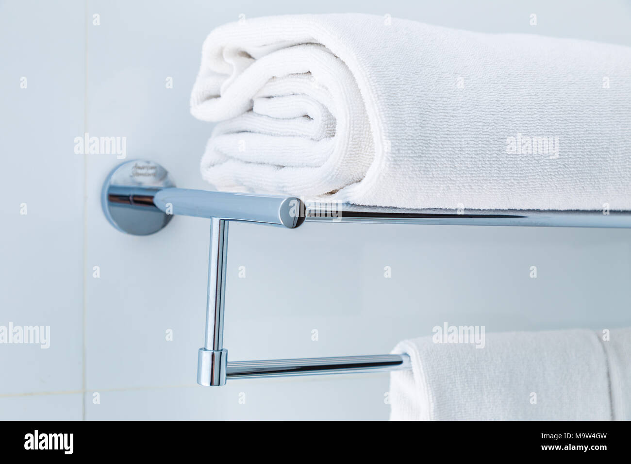 Close up of folded white bathroom towels on the rack in a white bathroom near shower, good for clean and fresh theme or refresh concept Stock Photo