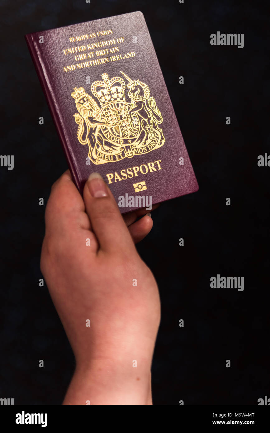Image of a persons hand holding a passport on isolated dark background