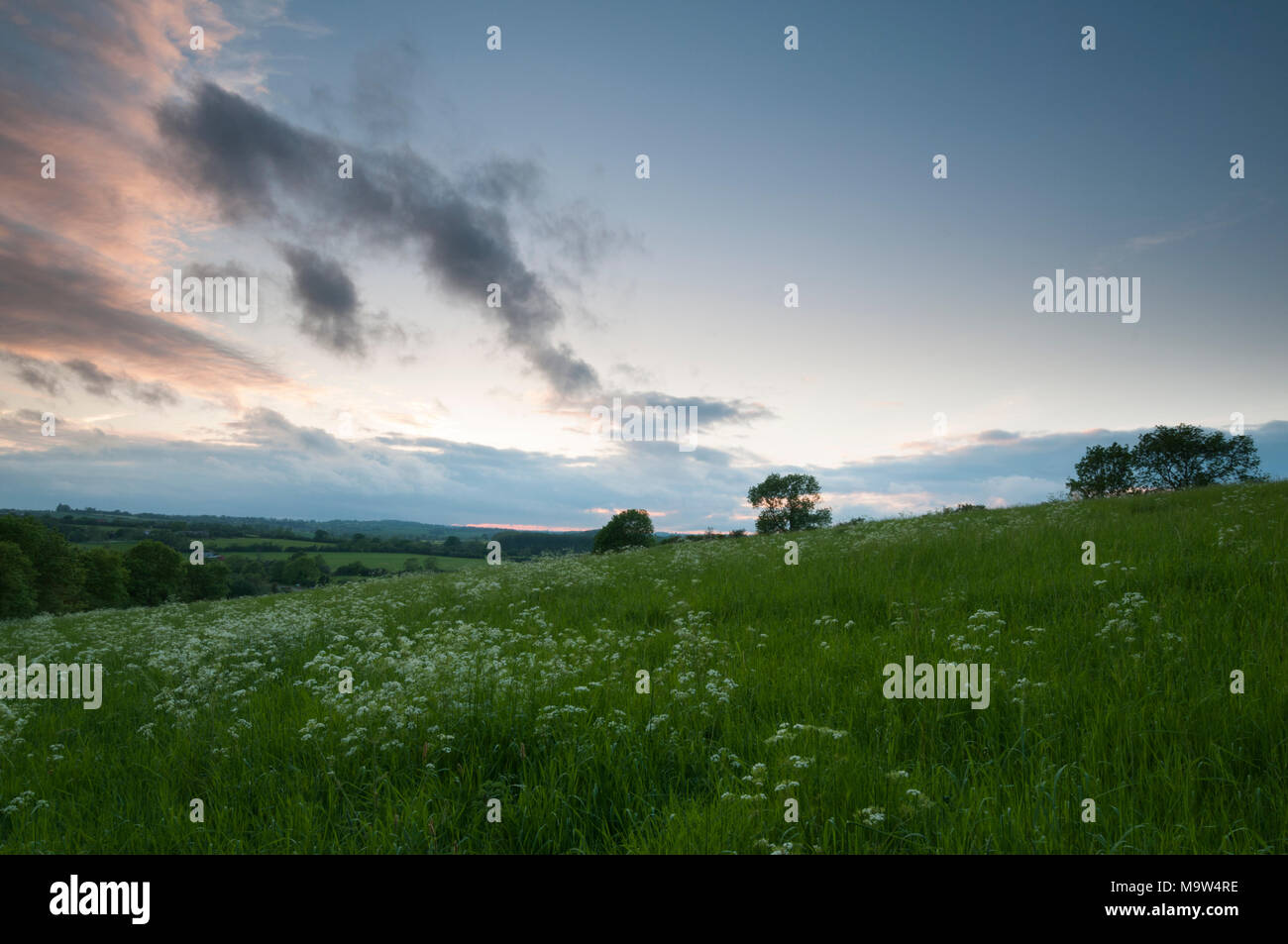 Cloud rolls in as the sun begins to set above a grassland meadow overlooking the Brampton valley near Brixworth in Northamptonshire, England. Stock Photo