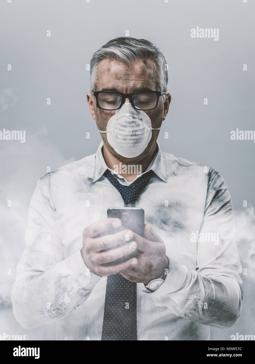 Corporate business executive with protective mask and smog, he is using a smartphone Stock Photo