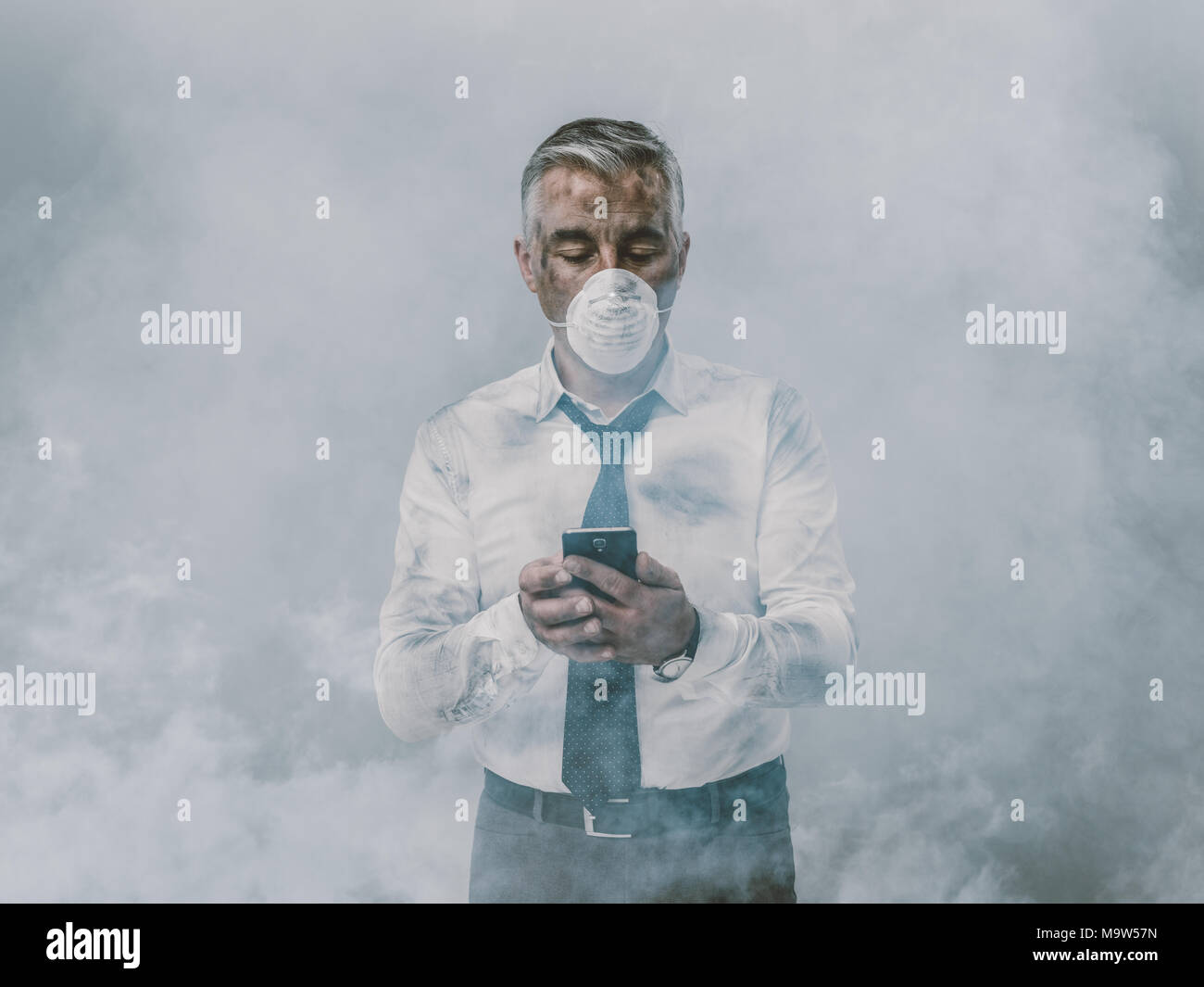 Corporate business executive with protective mask and polluted air, he is using a smartphone Stock Photo