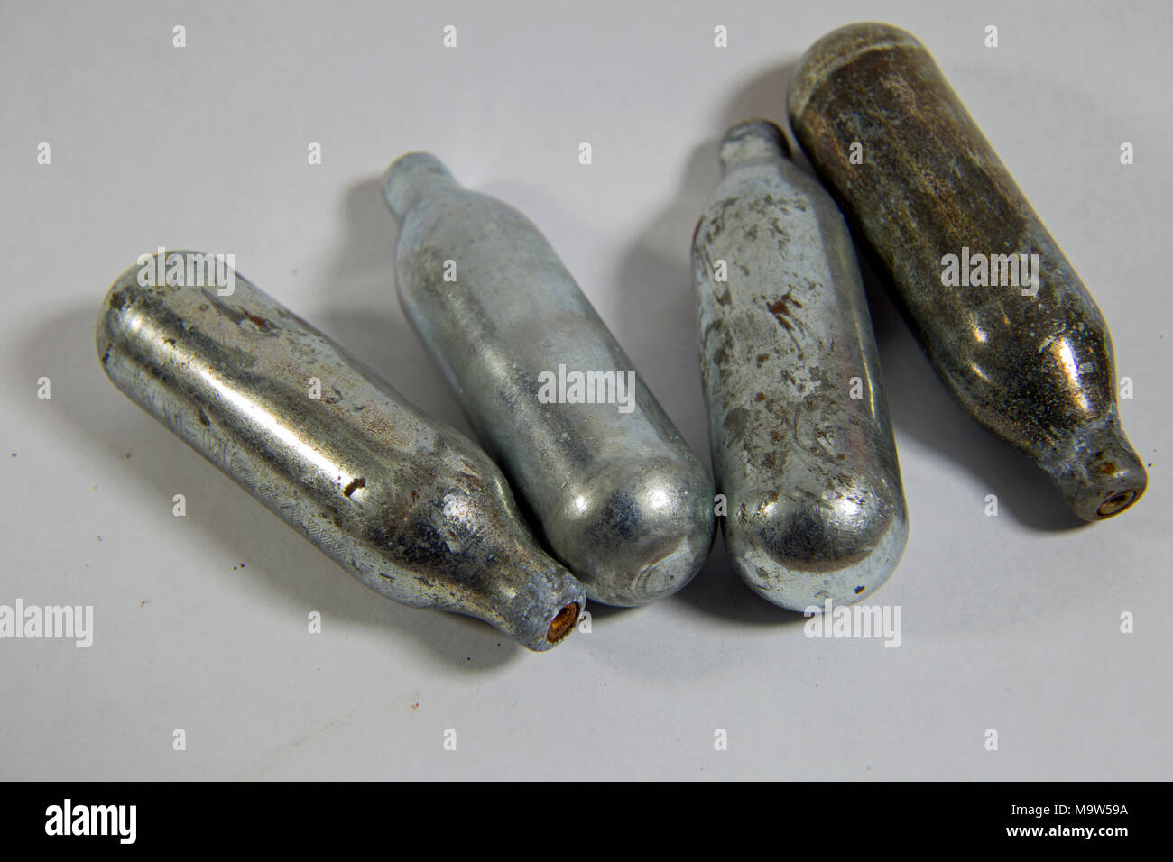 A close up studio shot of four Nitrous oxide gas bottles on a white