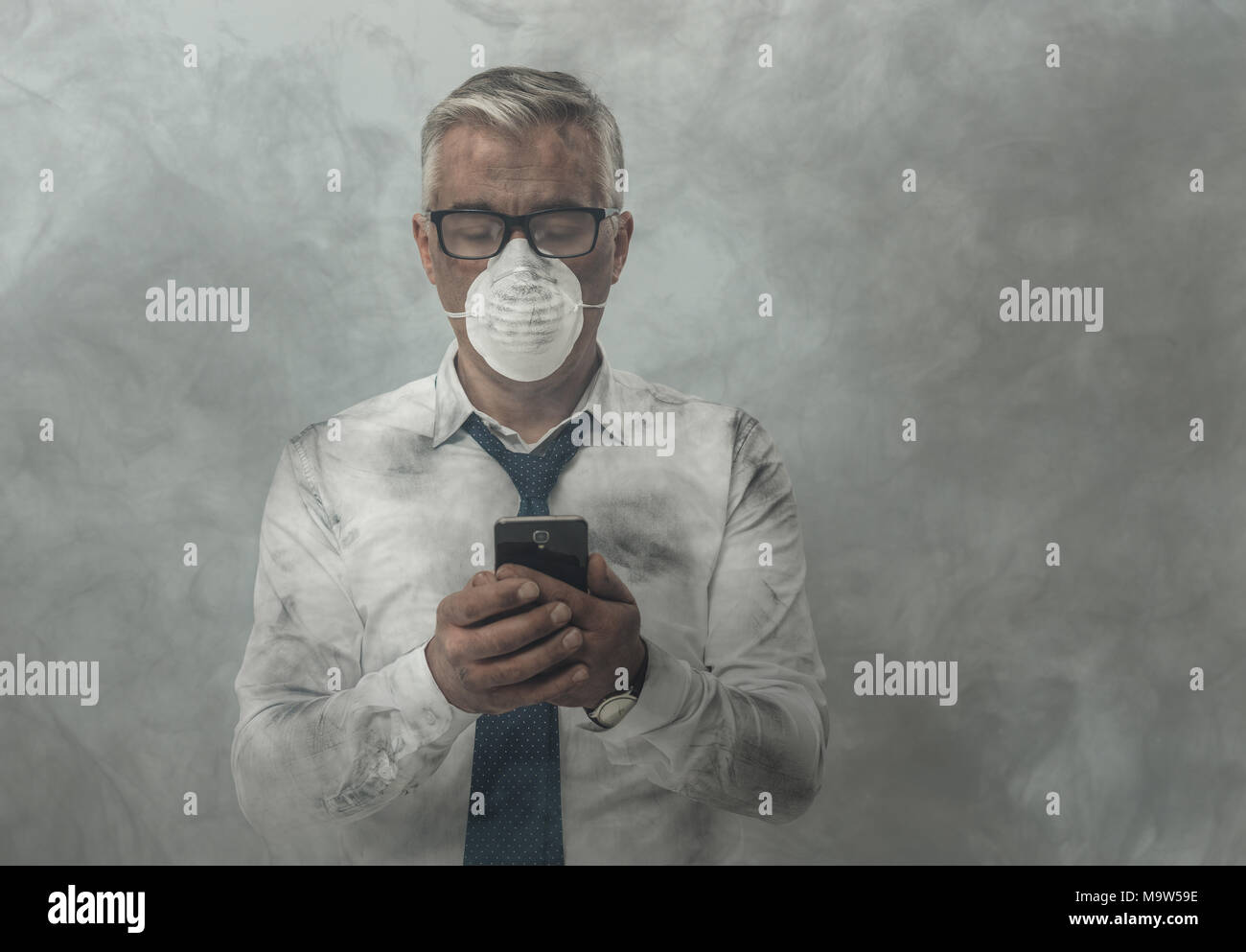 Corporate business executive with protective mask and smog, he is using a smartphone Stock Photo