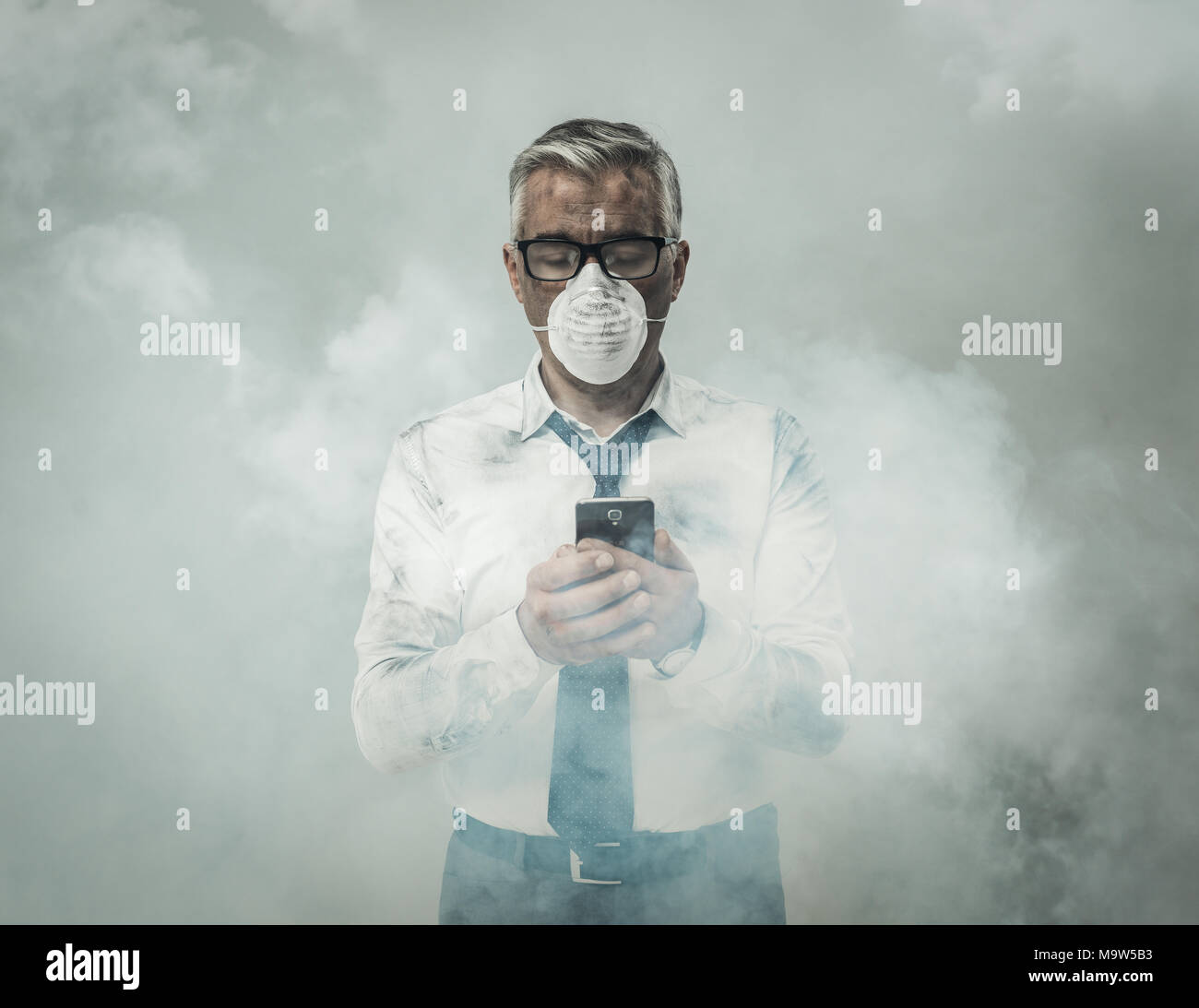 Corporate business executive with protective mask and smog, he is using a smartphone Stock Photo