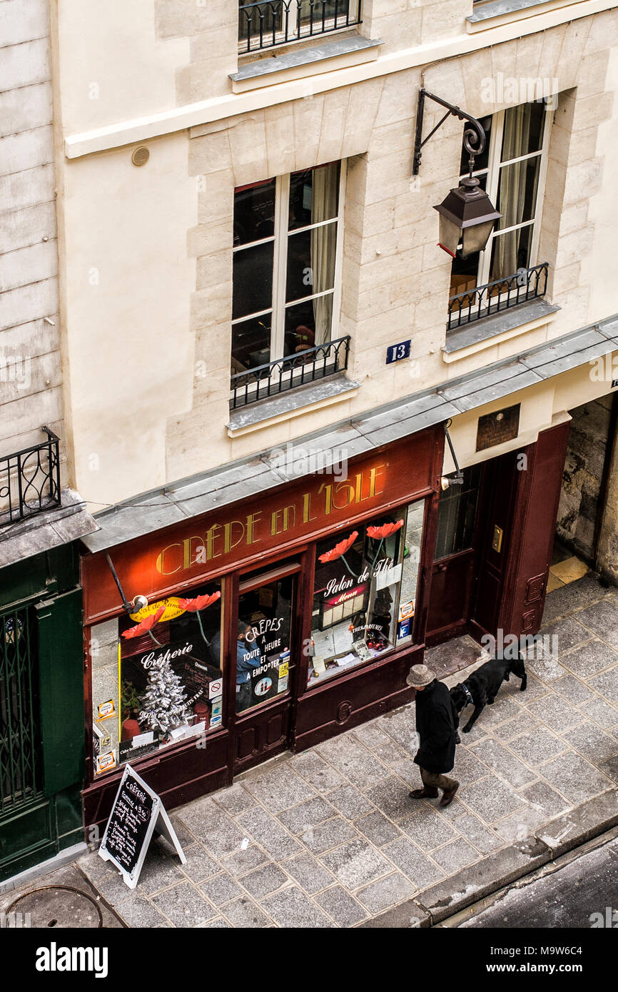 Man walking his dog in front of a creperie at Ile Saint-Louis. Paris, France. Stock Photo