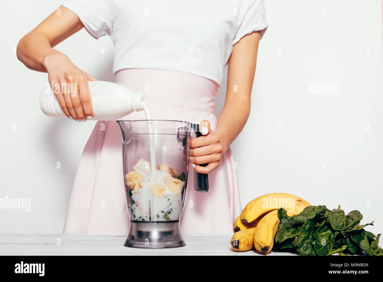 https://c8.alamy.com/comp/M9WB3X/young-woman-making-spinach-banana-smoothie-on-white-background-she-pouring-milk-in-blender-and-mix-ingredients-together-simple-elegant-picture-with-M9WB3X.jpg