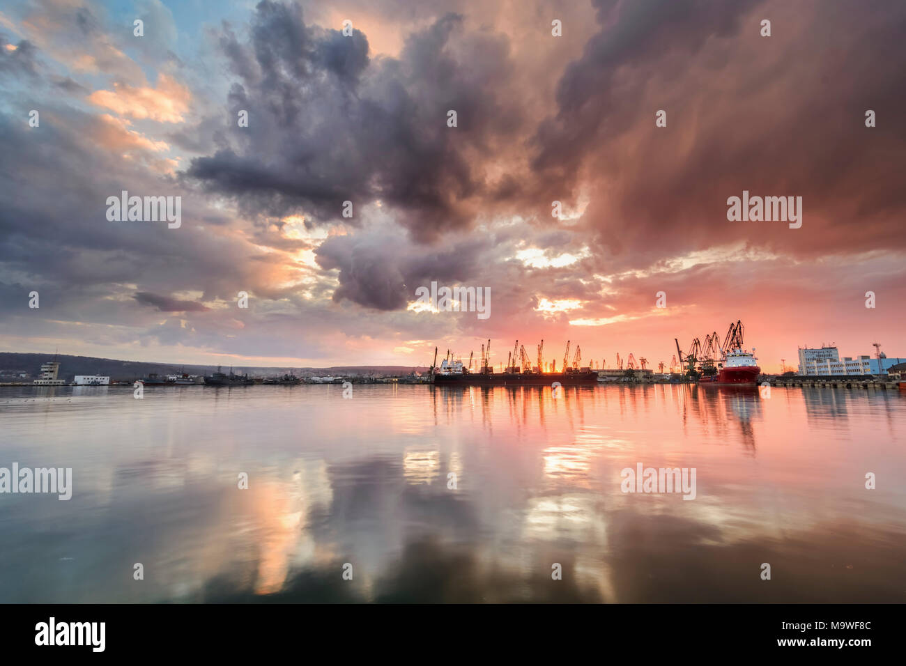 Silhouette of port cranes against a dramatic sky at sunset Stock Photo ...