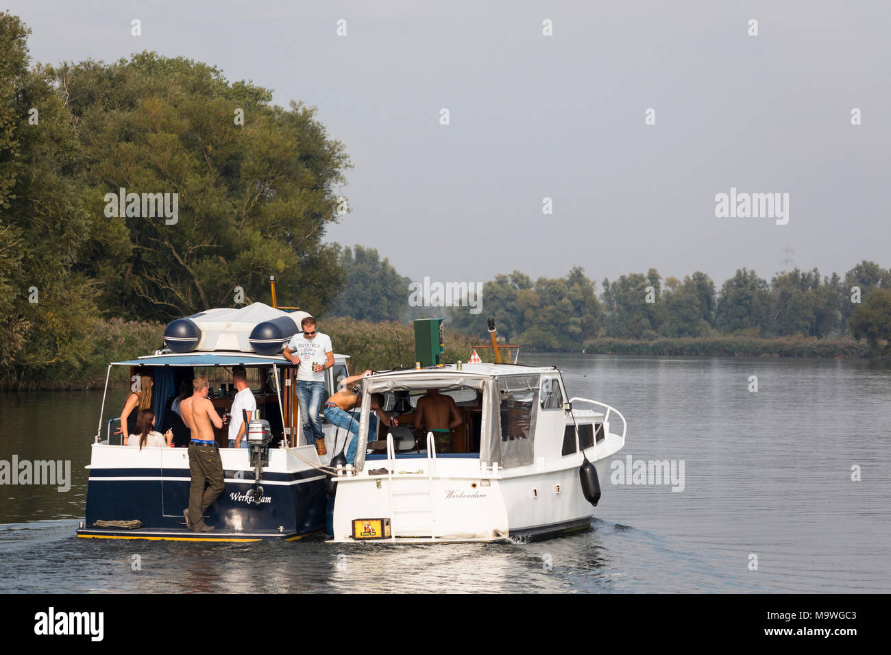 Group of young girls and boys having a party at two yachts at tnational park 'de Biesbosch' in the Netherlands Stock Photo