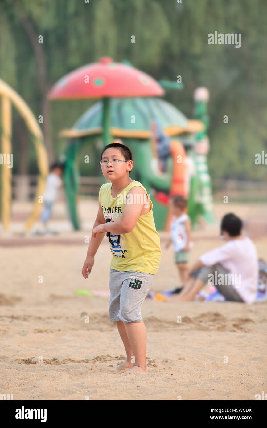 BEIJING-JULY 8, 2015. Young overweight boy on a beach. Changing diets and a sedentary lifestyle will cause 28% of seven to 18-year-old children. Stock Photo