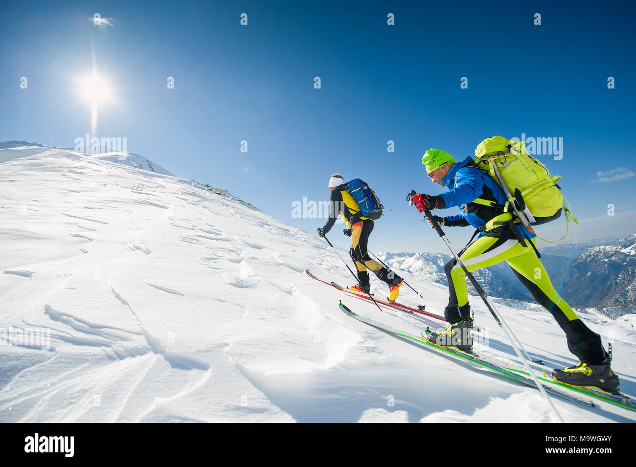 Cross country skiing team couple of men towards the summit of the mountain. Stock Photo