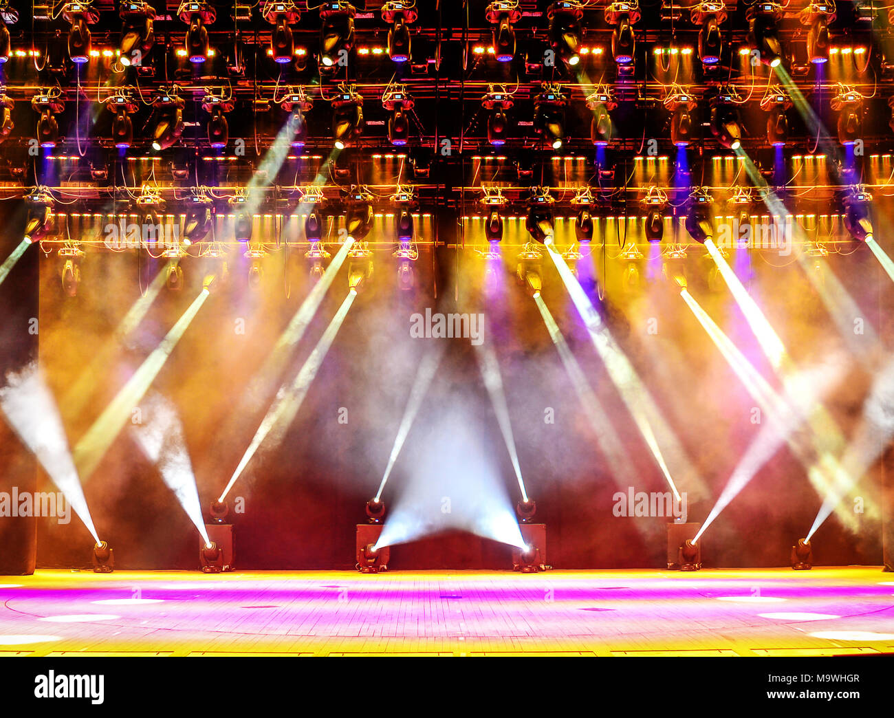 Illuminated empty concert stage with haze and rays of pink and yellow light. Background for music show Stock Photo