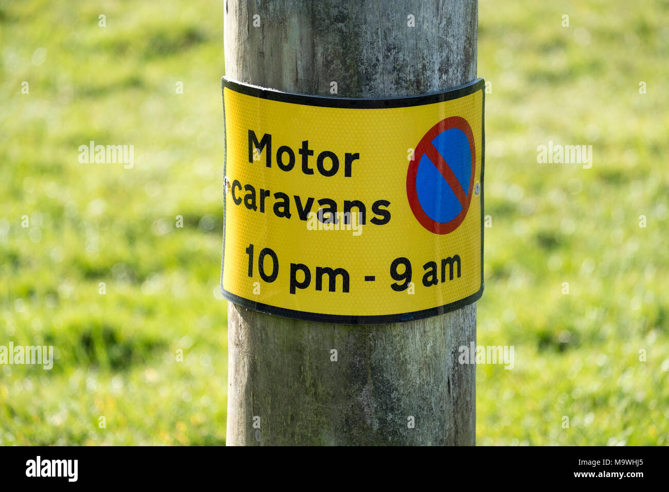 metal sign attached to wooden post stating that no motor caravans between 10 pm and 9 am. Stock Photo