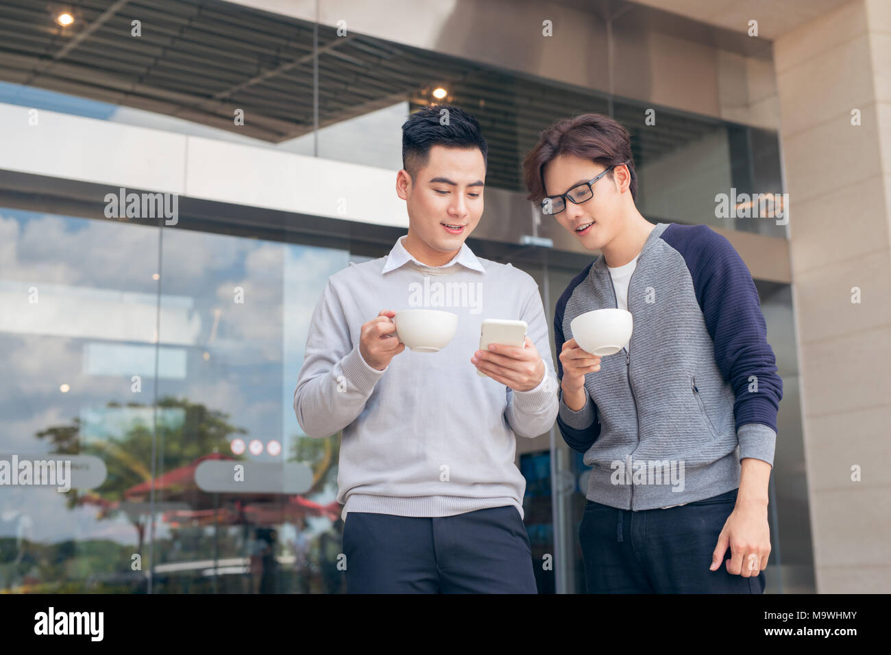 Two smiling businessmen walking and talking in the city Stock Photo - Alamy