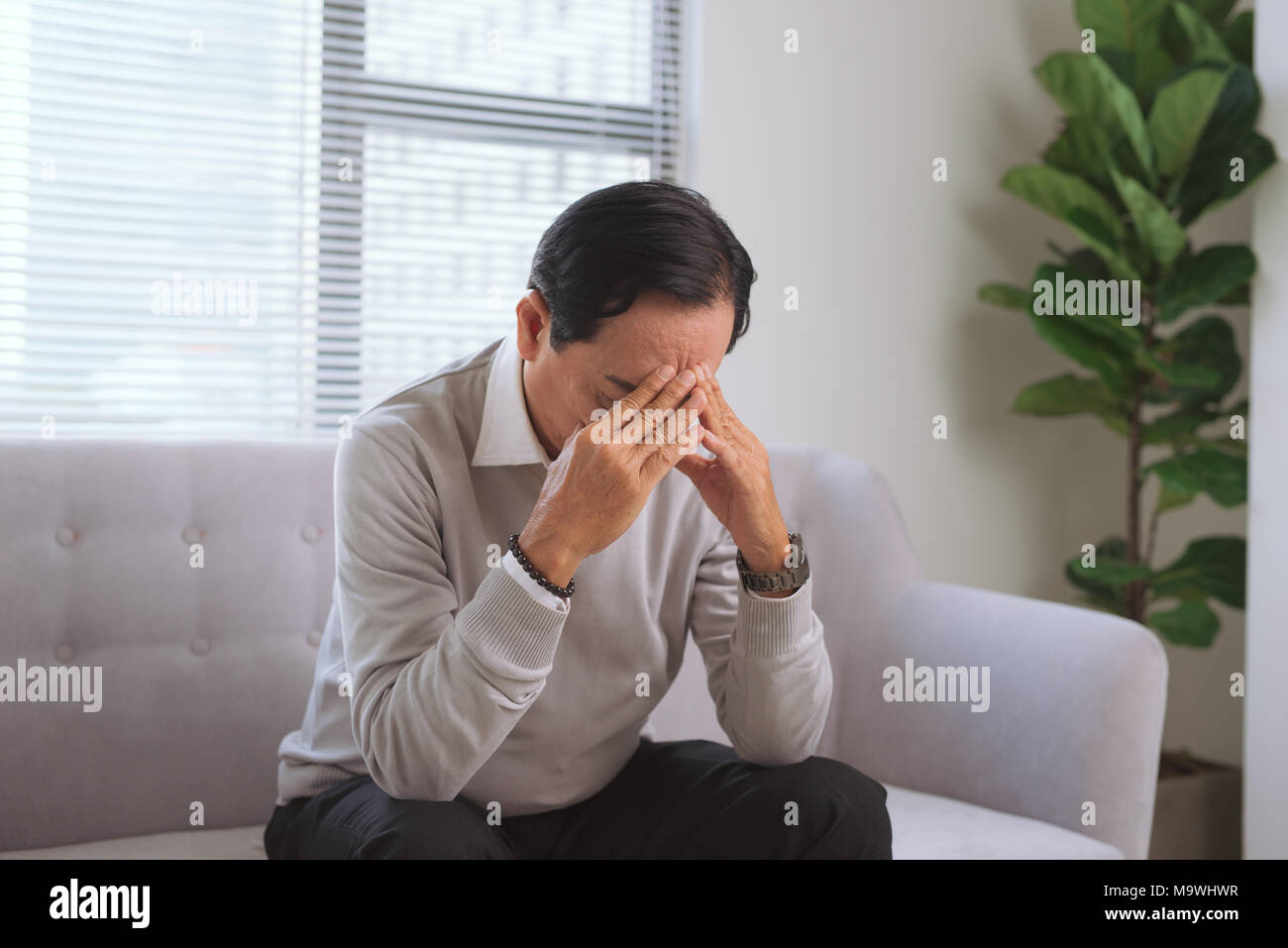 Sad senior man sitting on couch hi-res stock photography and images - Alamy