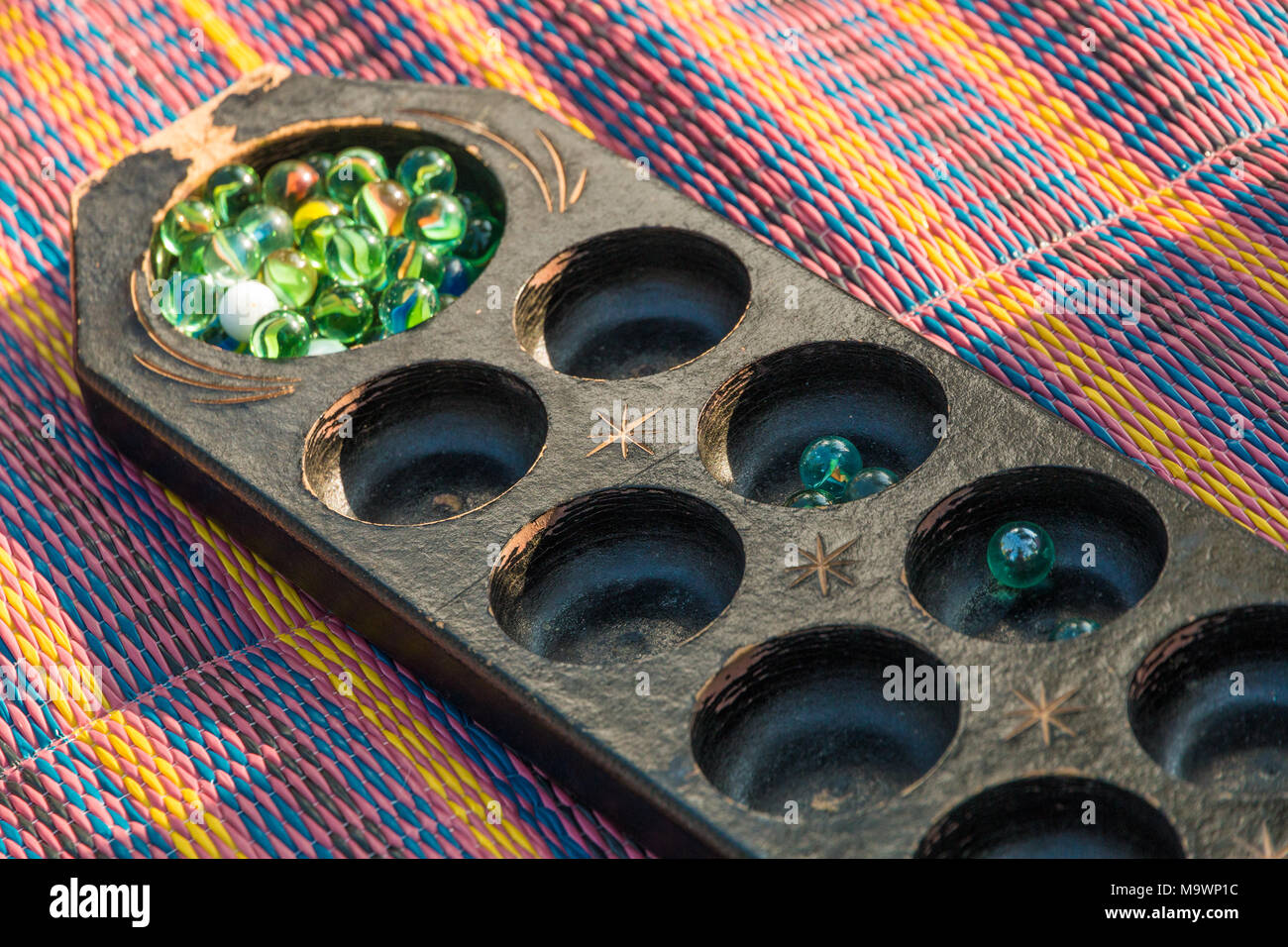 Close-up of a congkak or congklak which is a mancala marble game of Malay origin. Stock Photo