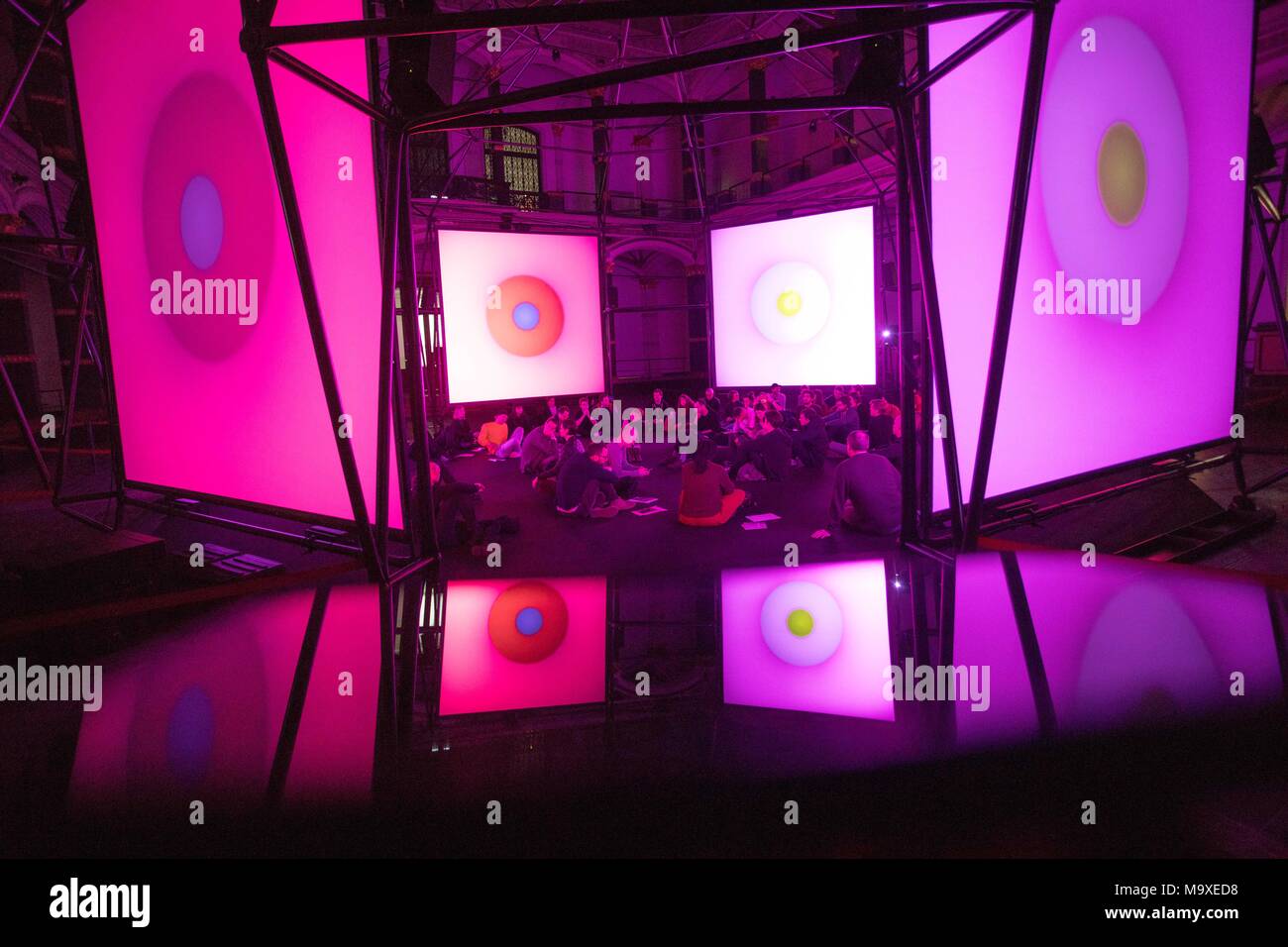 29 March 2018, Germany, Berlin: The installation 'Empty Formalism' by Brian Eno in the 'ISM Hexadome' in the Martin Gropius Building reflected by a smartphone. The installation displays colourful and continuously changing surfaces on canvas while spherical sounds play. The work is part of the exhibition 'ISM Hexadome'. Photo: Jörg Carstensen/dpa Stock Photo